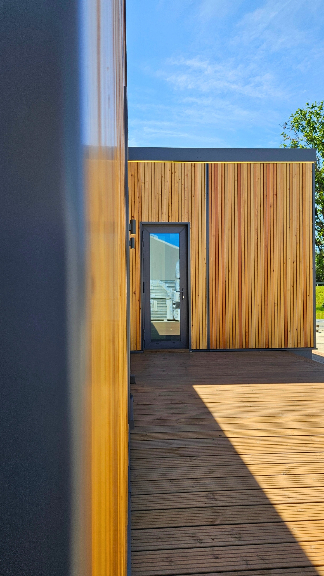 Timber terrace and entrance door of a TheHouz modular home in sunlight